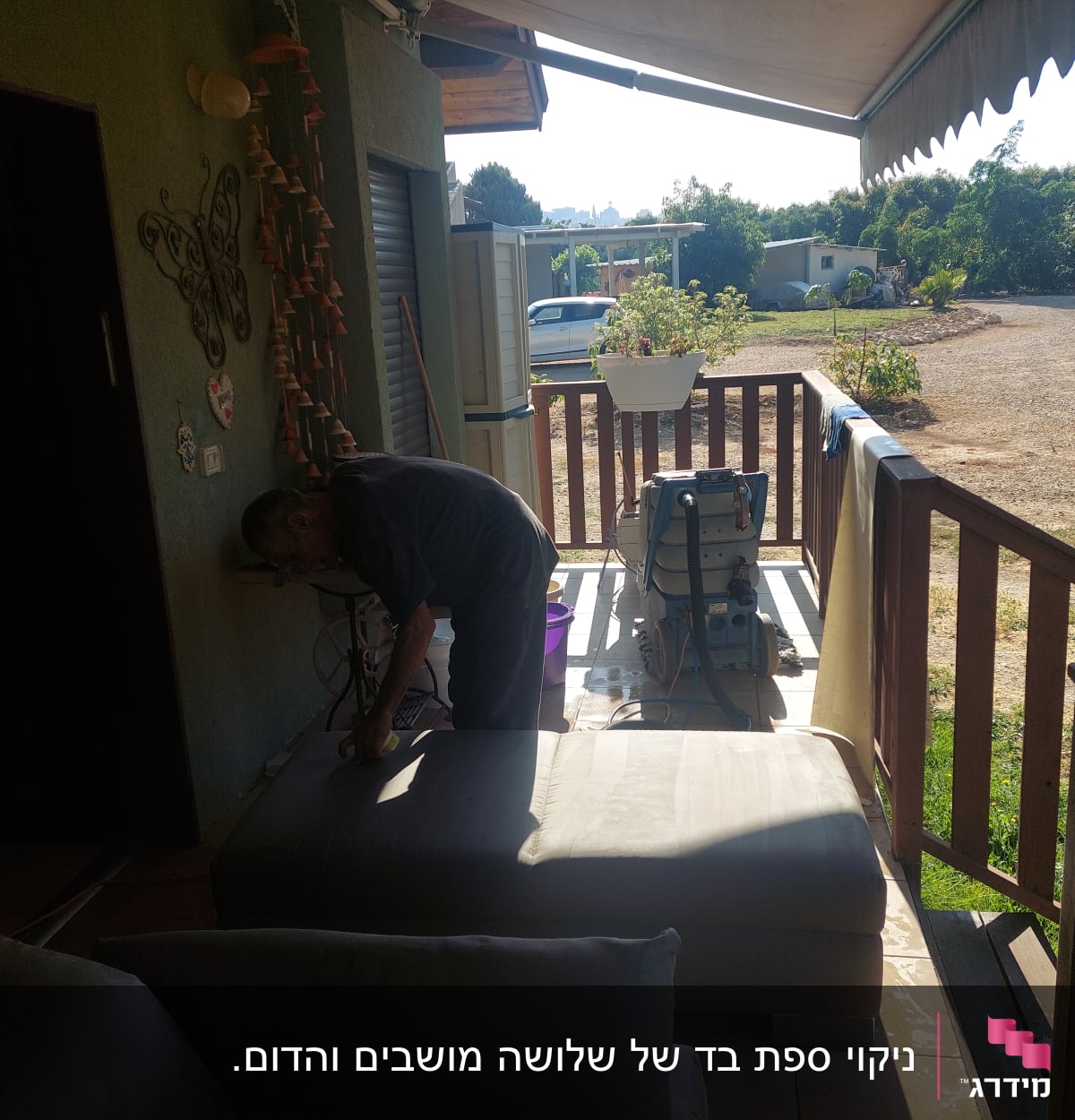 אדם מנקה ספה עם מכונת ניקוי במרפסת